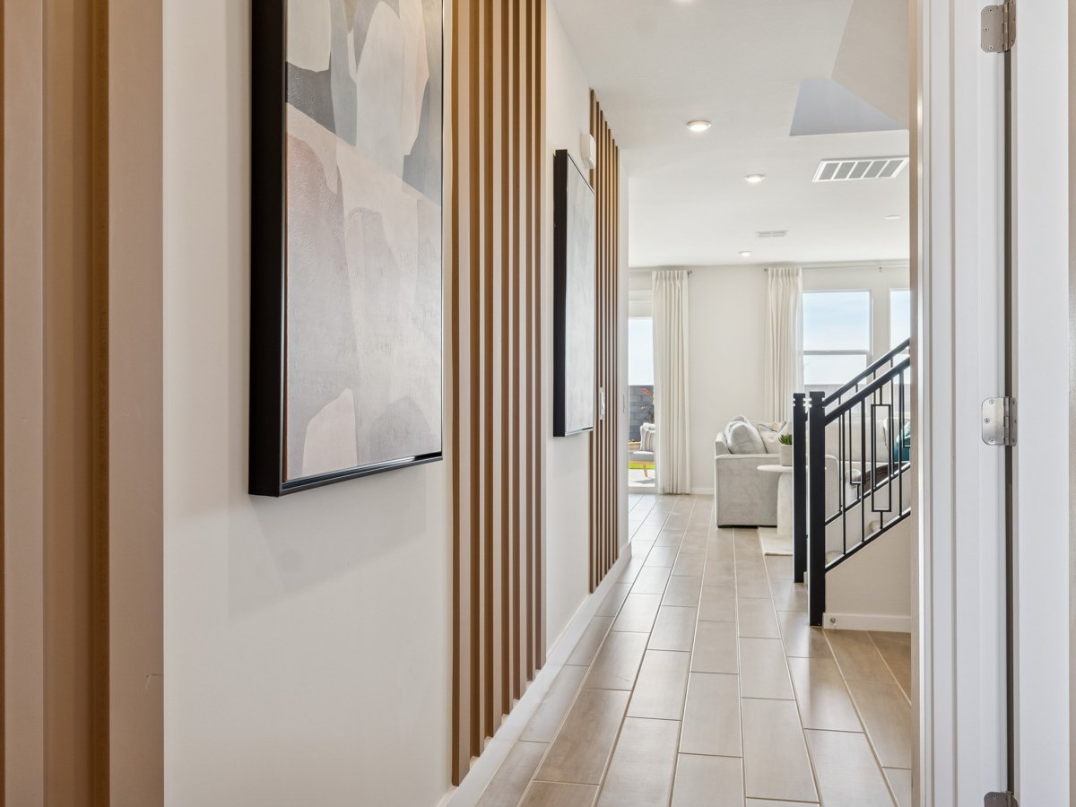 A hallway with a railing and a door with a painting on the wall.