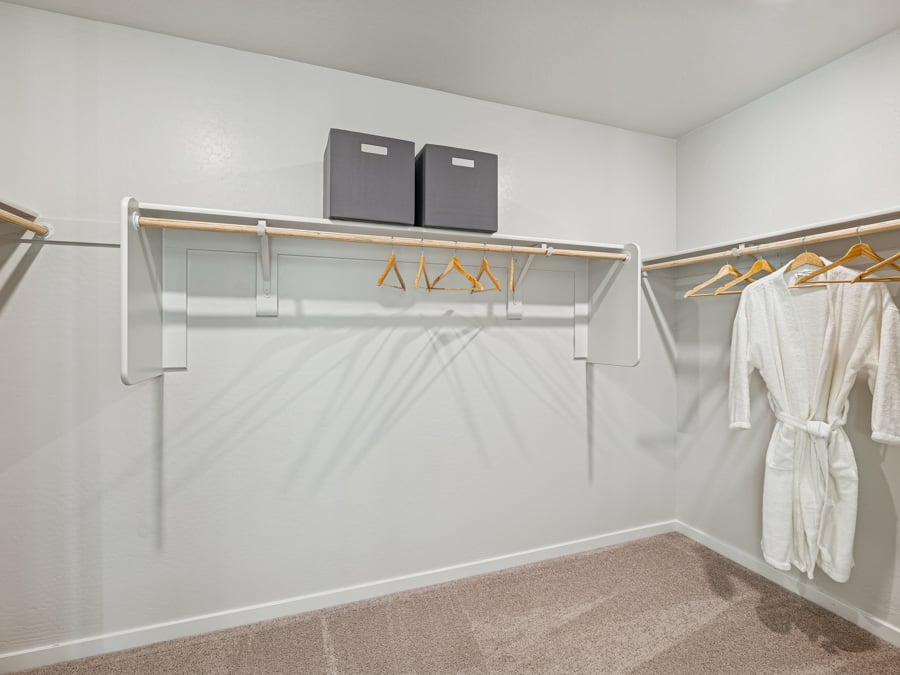 A white shower with a television and clothes on the wall.