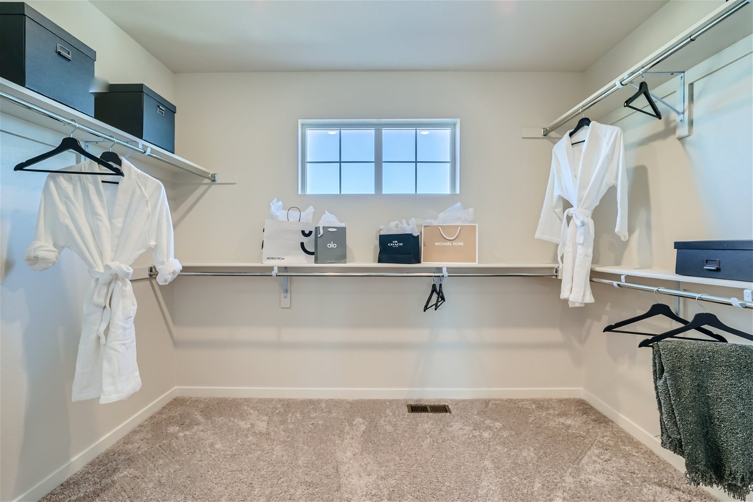 A room with white clothes on the wall and a window.