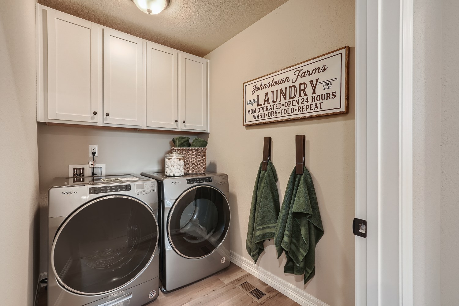 A laundry room with white cabinets.