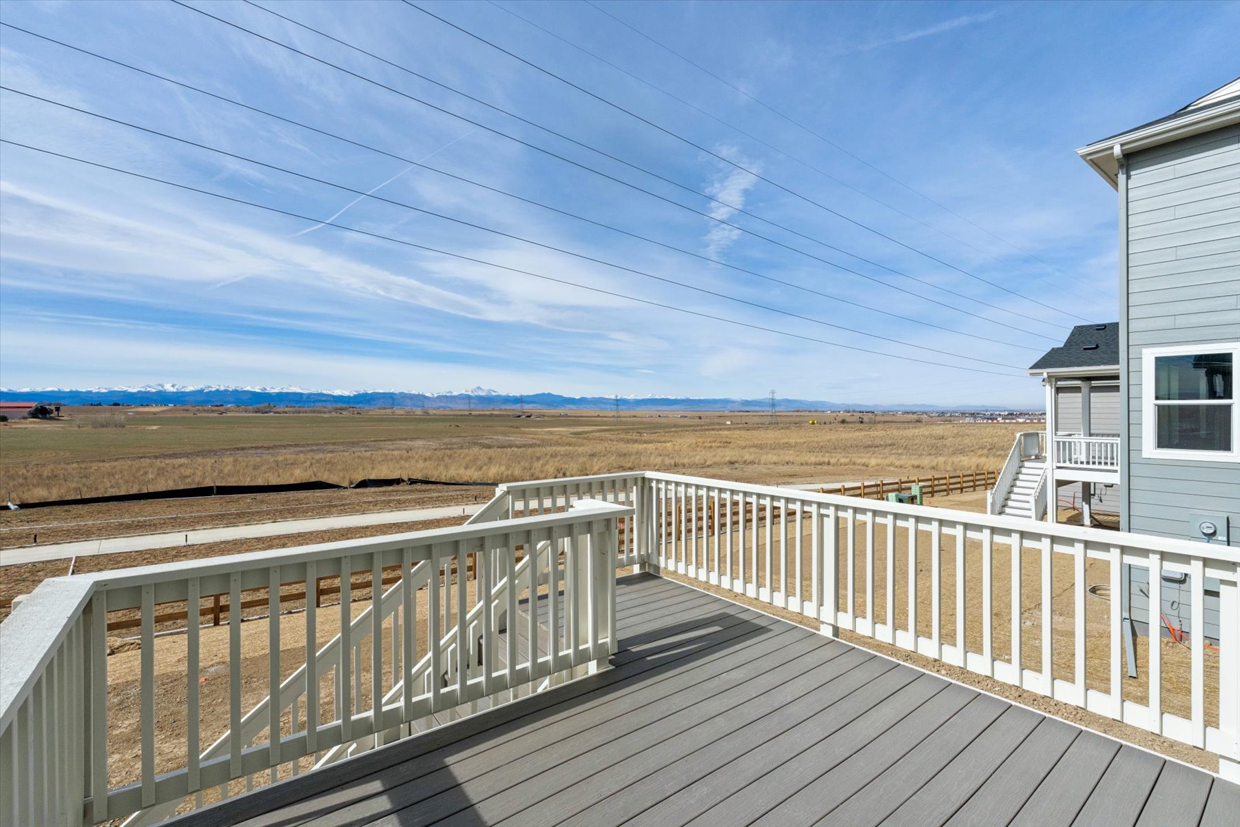A wooden deck with a building and a field in the background.