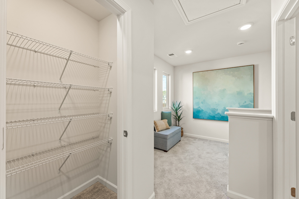 A room with a white wall and a painting on the wall.