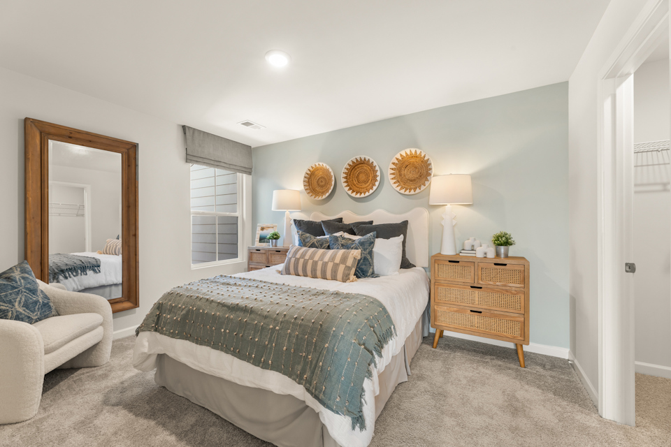 A bedroom with a bed and a mirror.