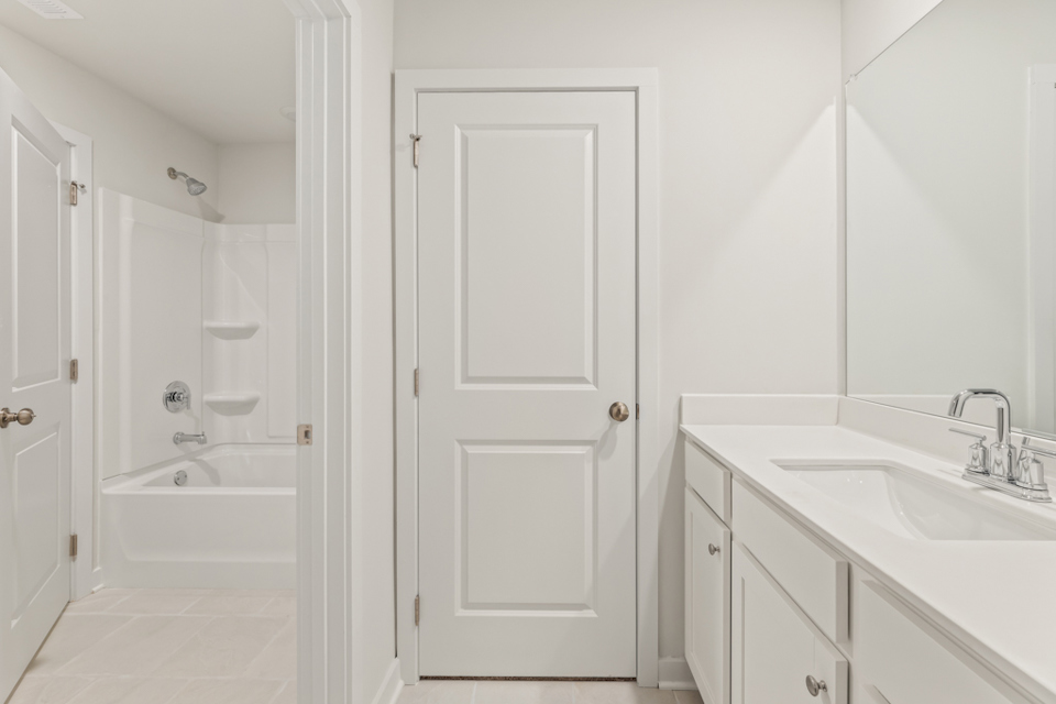 A bathroom with white cabinets.