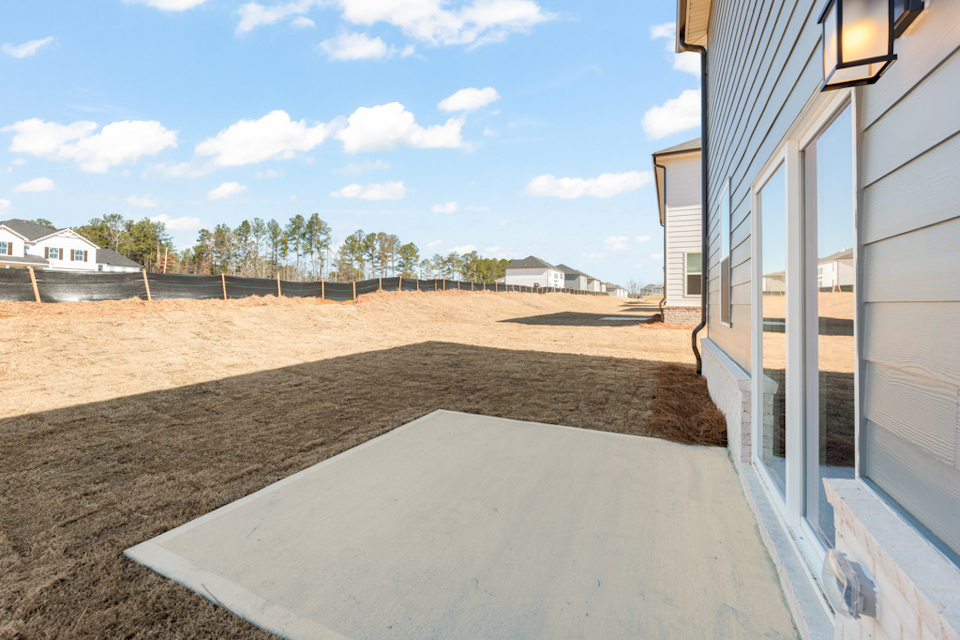 A sandy area with a fence and trees in the background.