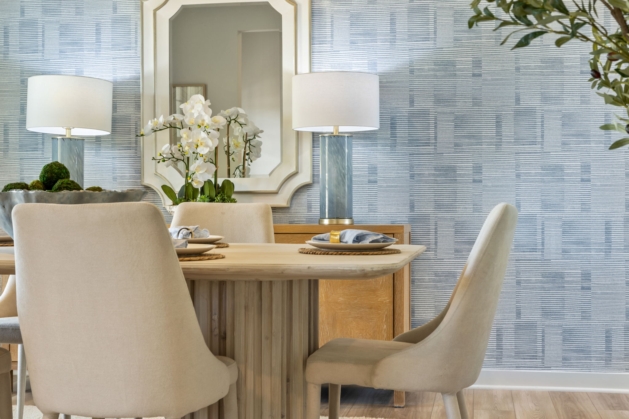 A dining table with chairs and a window with a plant on it.