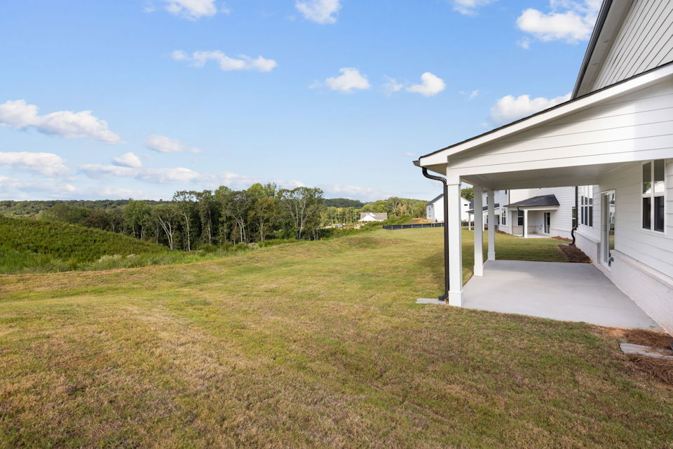 A house with a lawn and trees in the back.