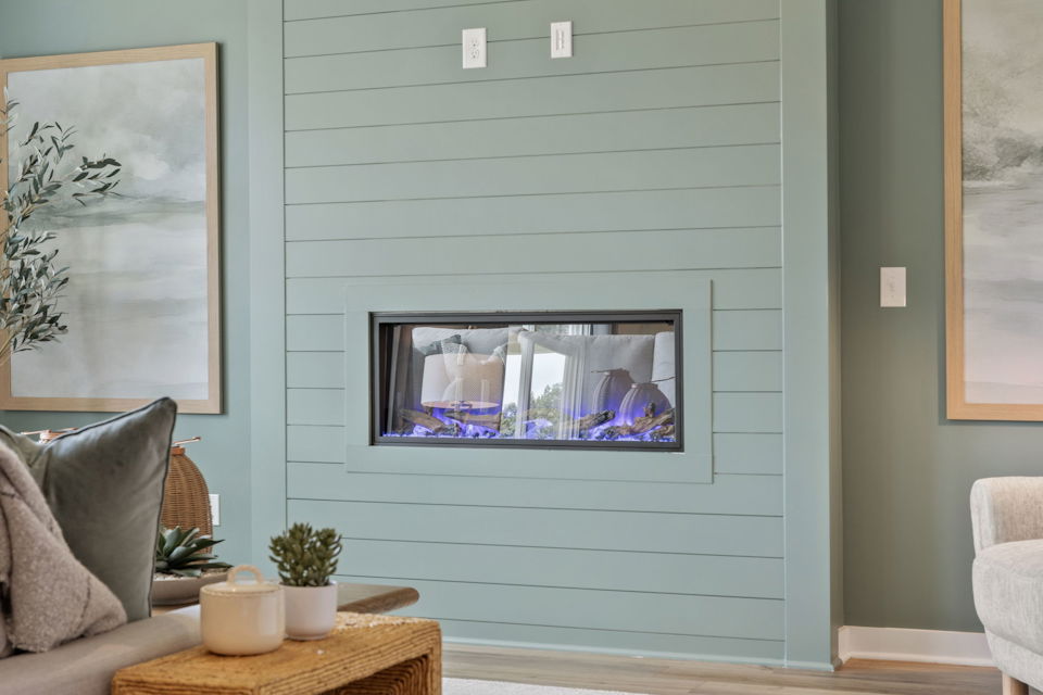 A room with a television and a table with a plant and a chair.