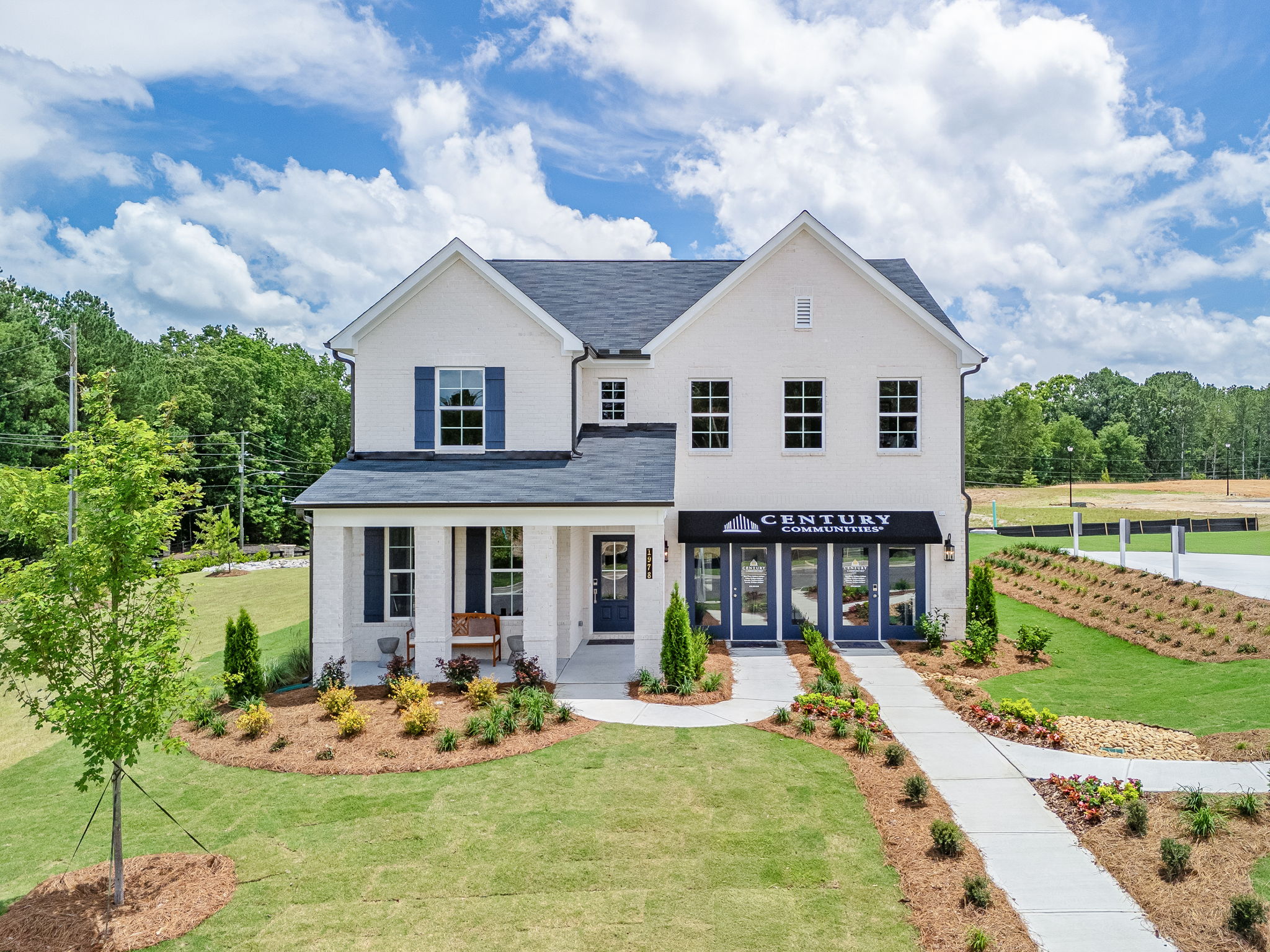 A white house with a lawn and trees in front of it.