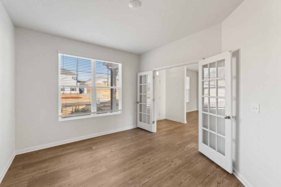 A room with a wood floor and a window with a view of a city.