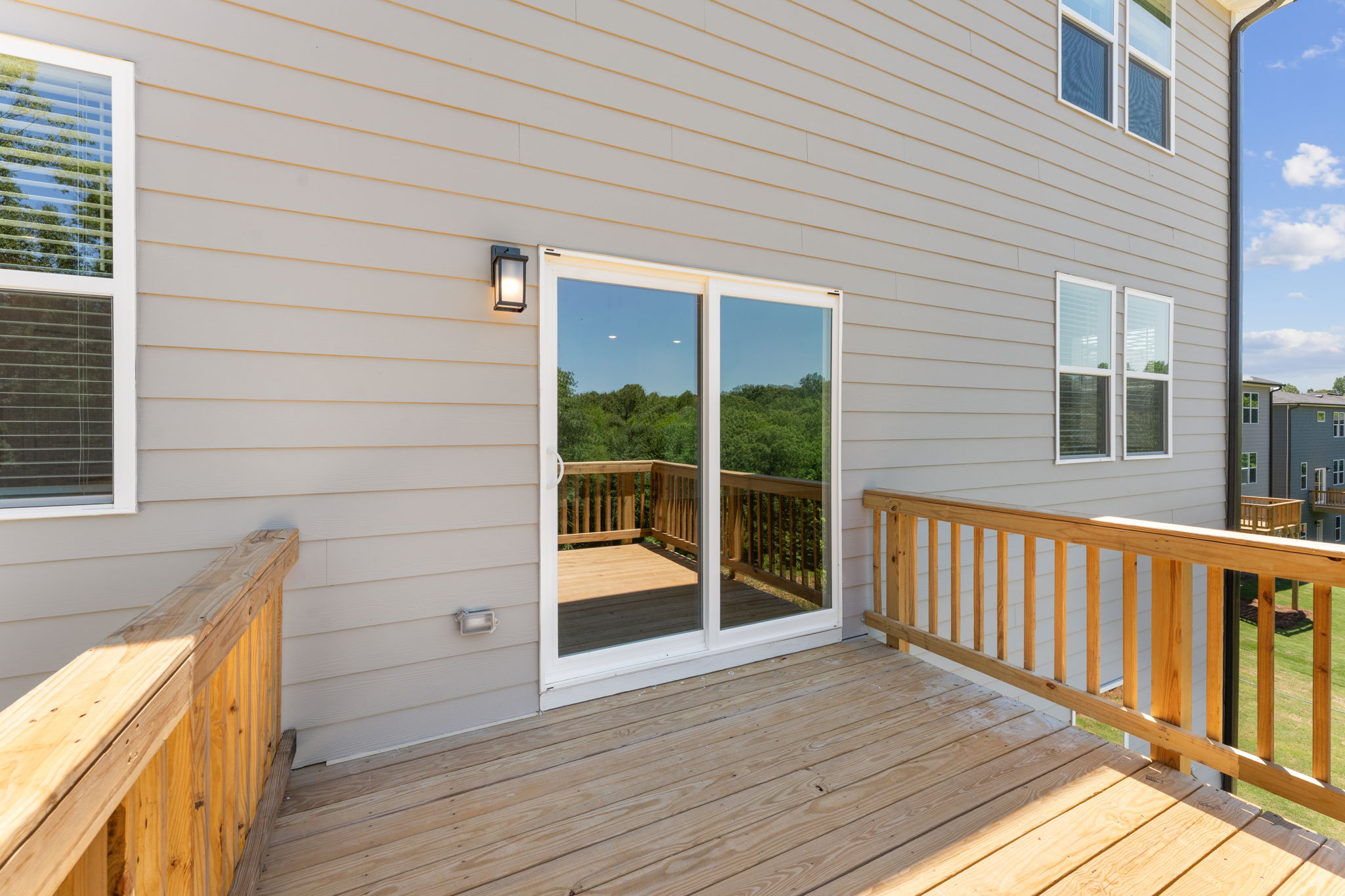 A deck with a wood railing and a wood railing with a view of the ocean and trees.