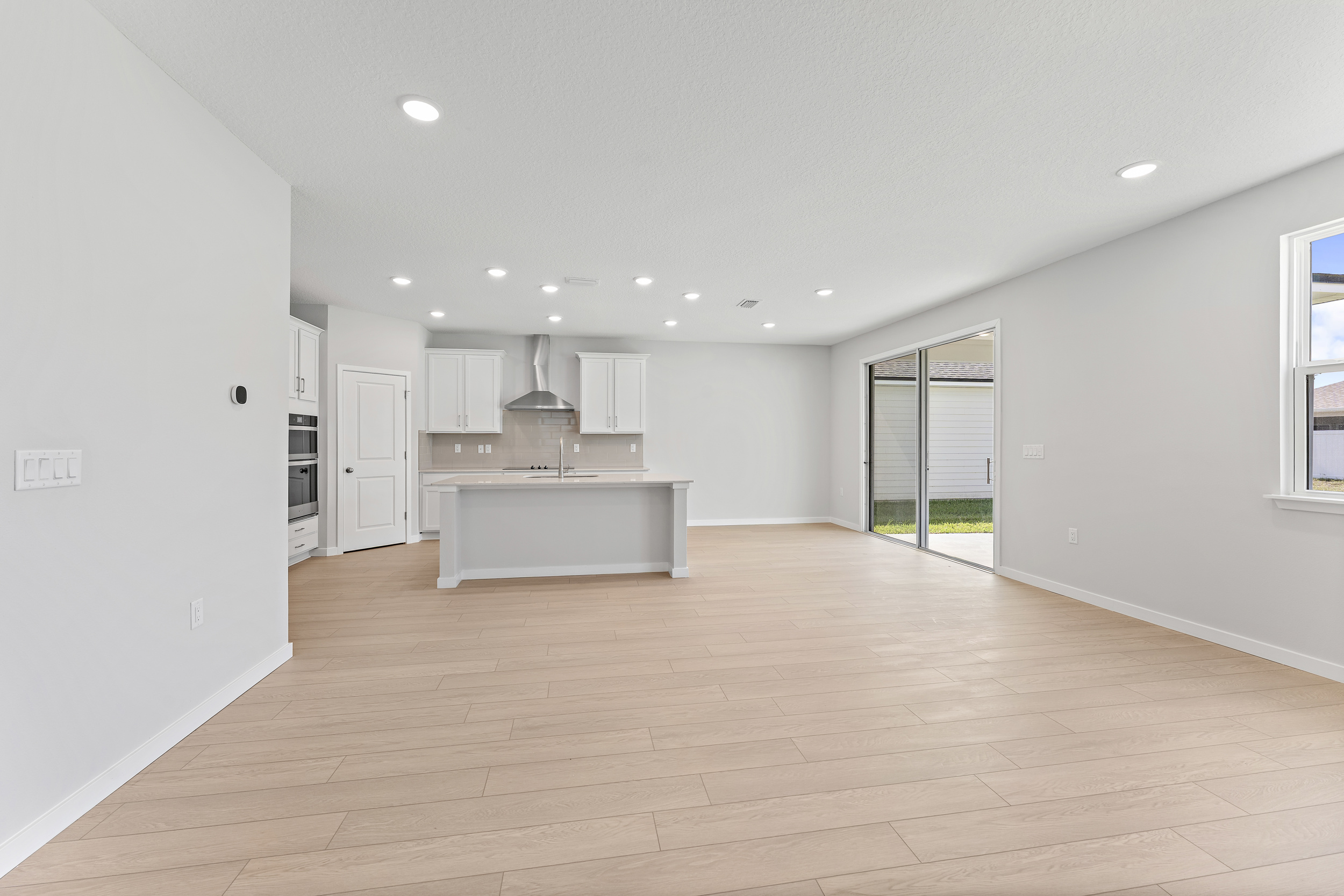 Lot 20 Ponderosa II Living Area Looking at Kitchen and Sliding Patio Doors at Camden Woods in Kingsland, GA