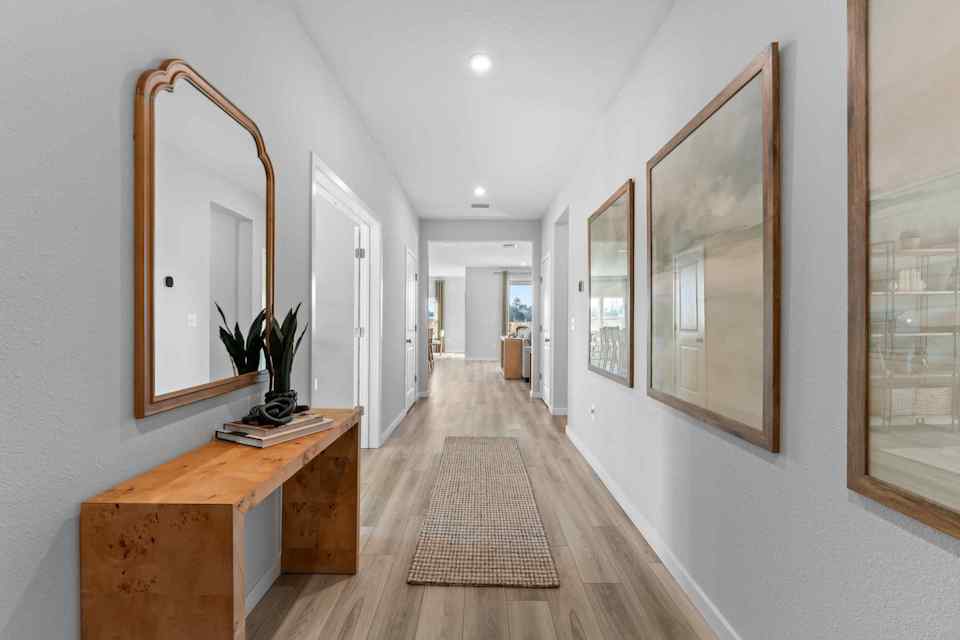A long hallway with a mirror and a table.