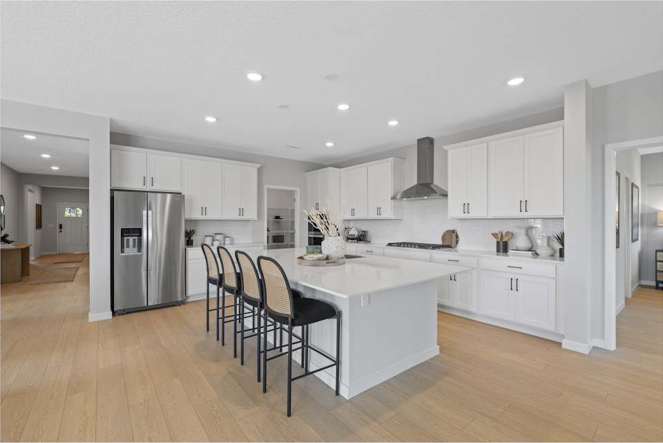 Kenai Model Home Kitchen with Island and White Cabinets at Reserve East in Flagler Beach