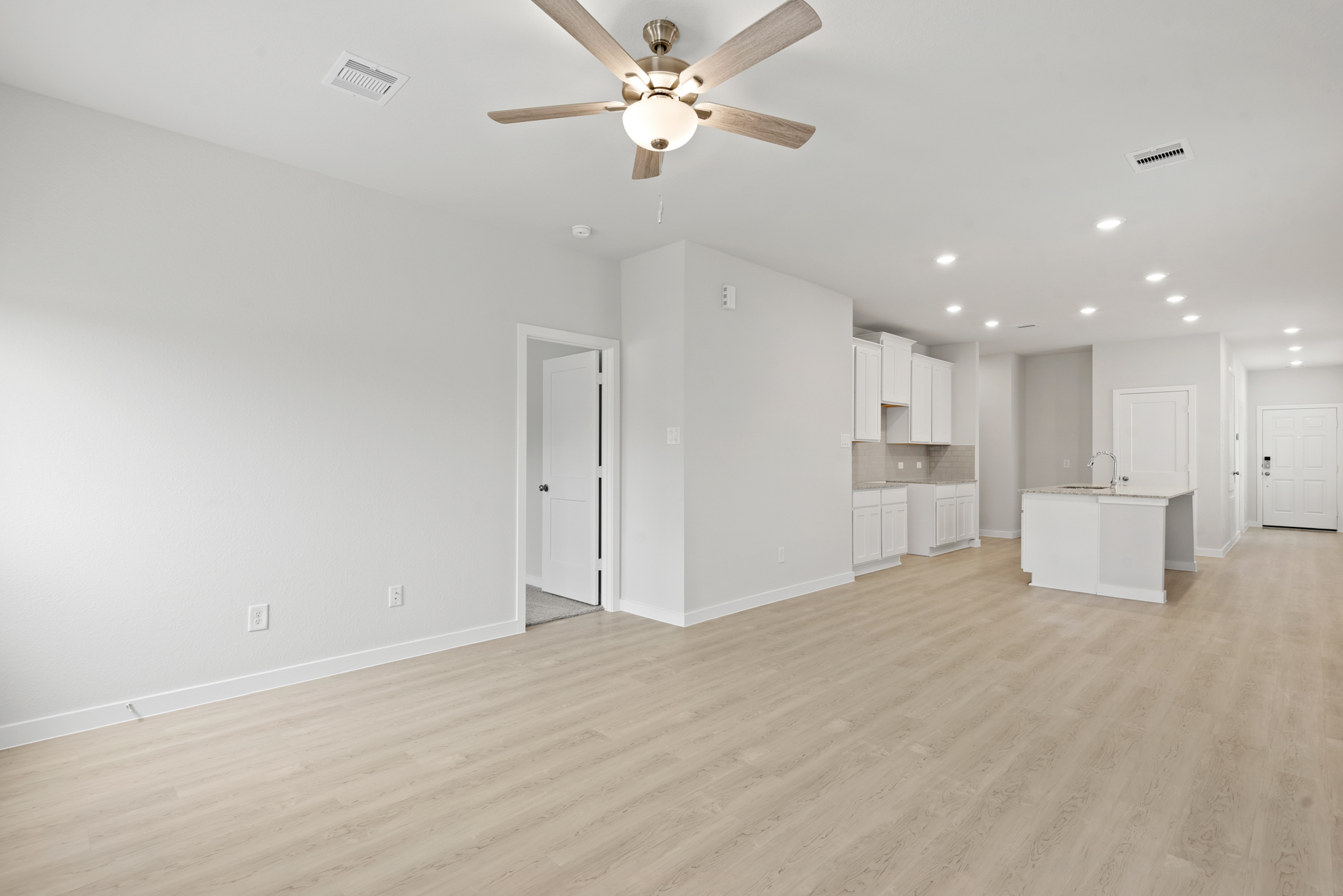 A large empty room with white cabinets.