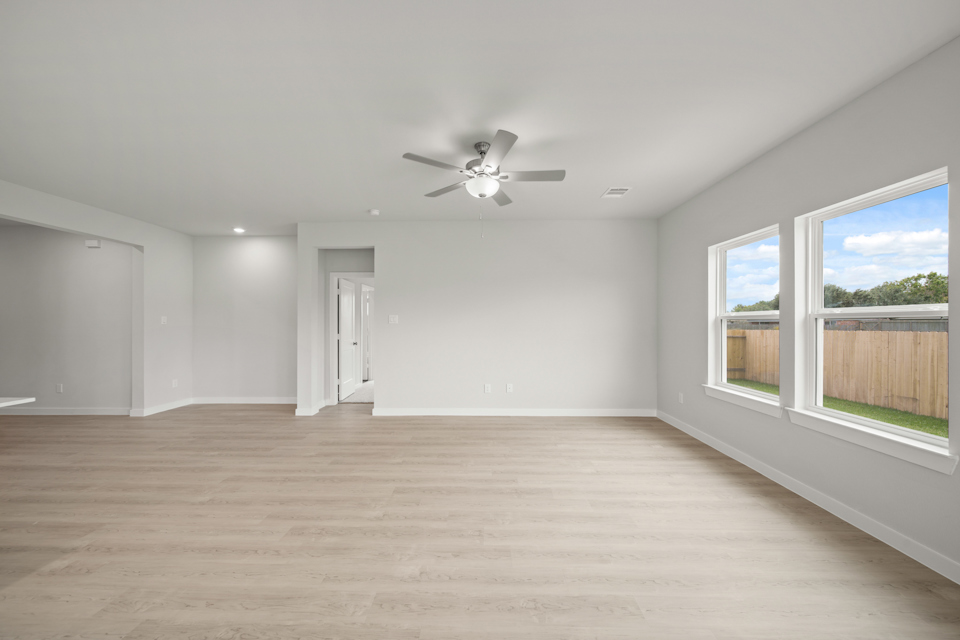 A room with a ceiling fan and windows.