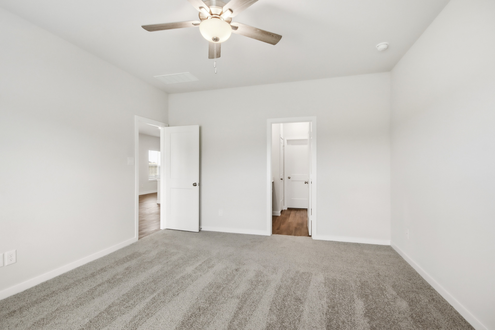 A room with a ceiling fan and a door.