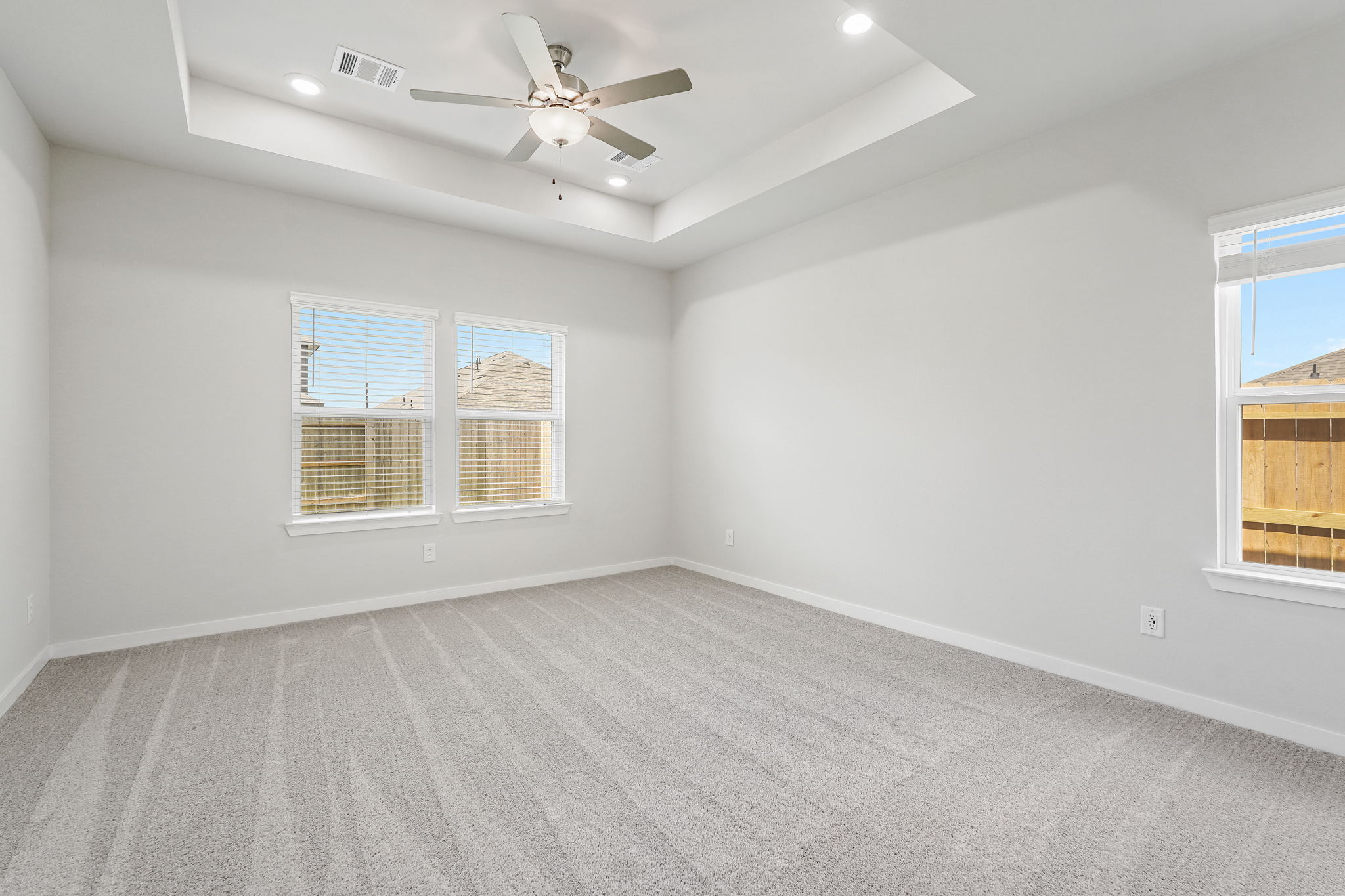 A room with a ceiling fan and windows.