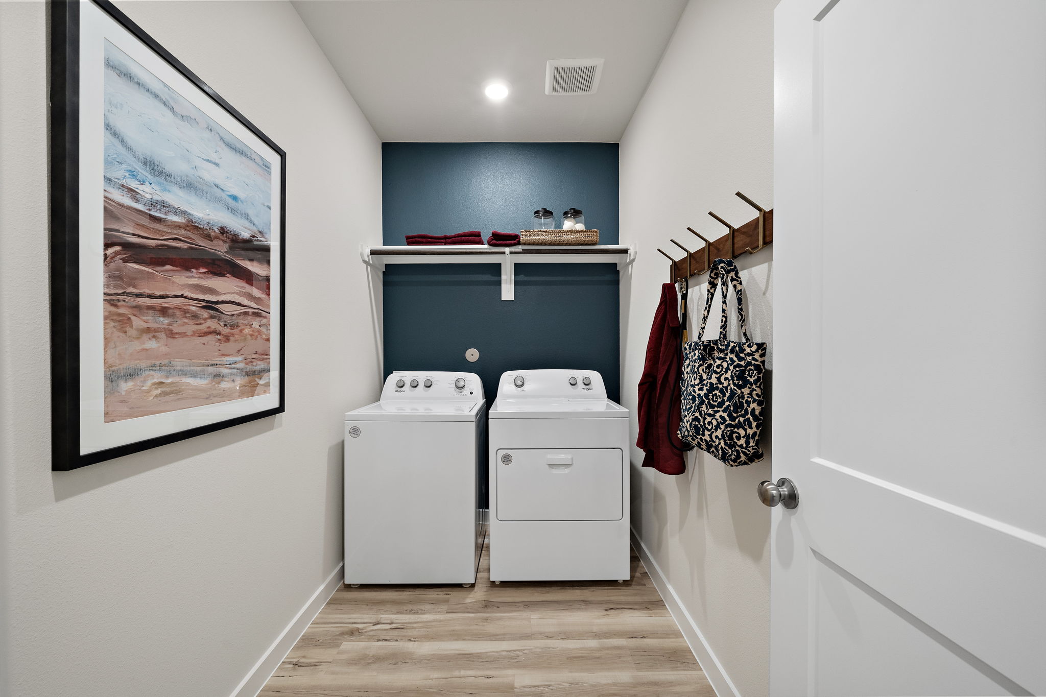 A room with a white cabinet and a white wall with a picture on it.