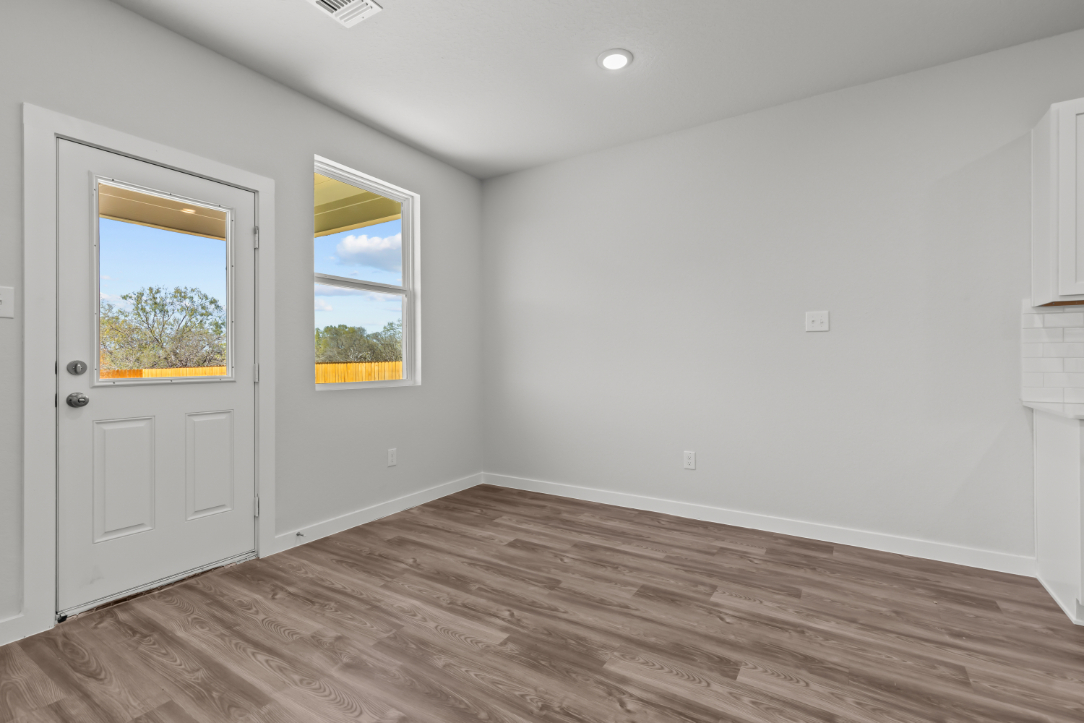 A room with white walls and a wood floor with a window.