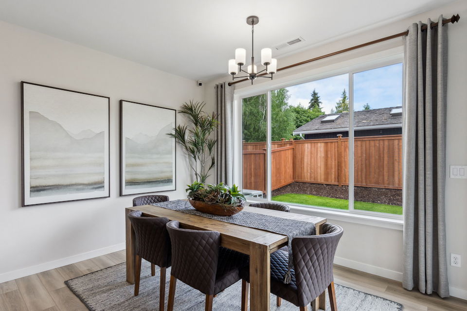 A dining room table with chairs and a window with a view of the ocean.