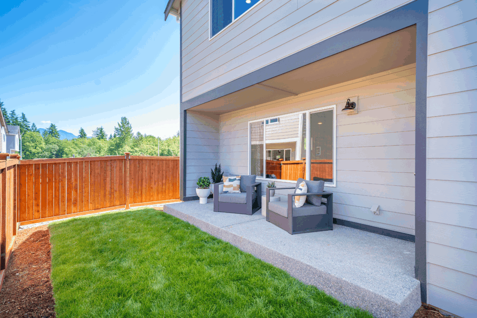 A house with a deck and a dog sitting on a bench.