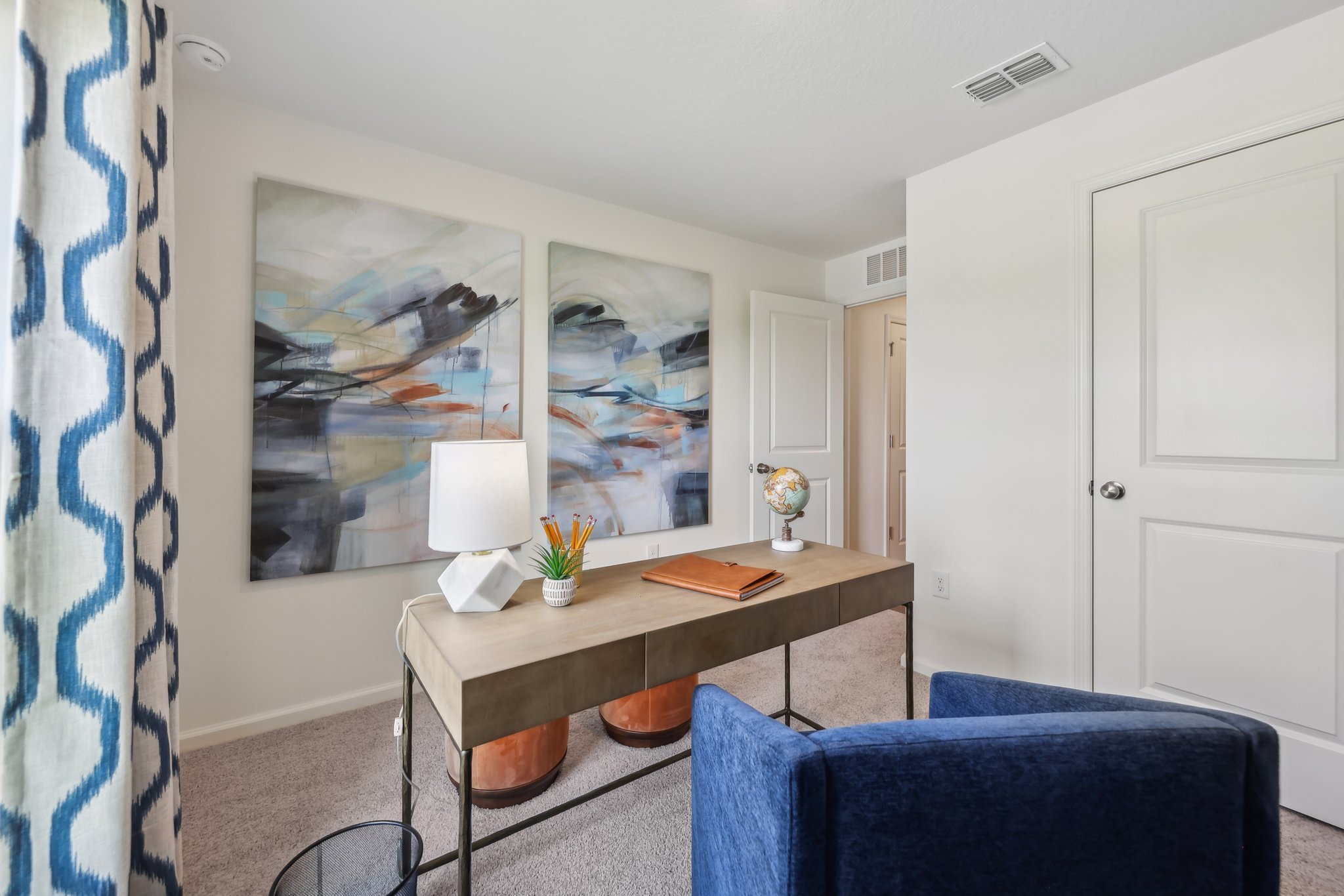 A desk with a lamp and a chair in a room with a window.